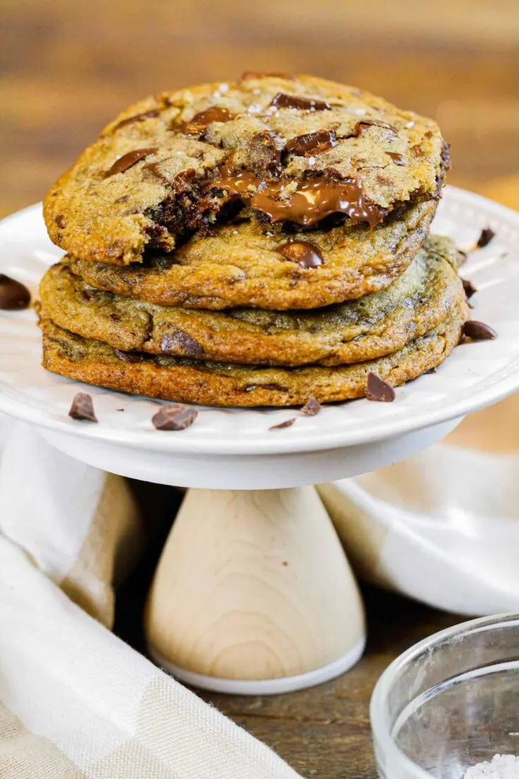 image of brown butter Nutella chocolate chip cookies in a stack with the top cookie bitten into showing the warm, melting nutella