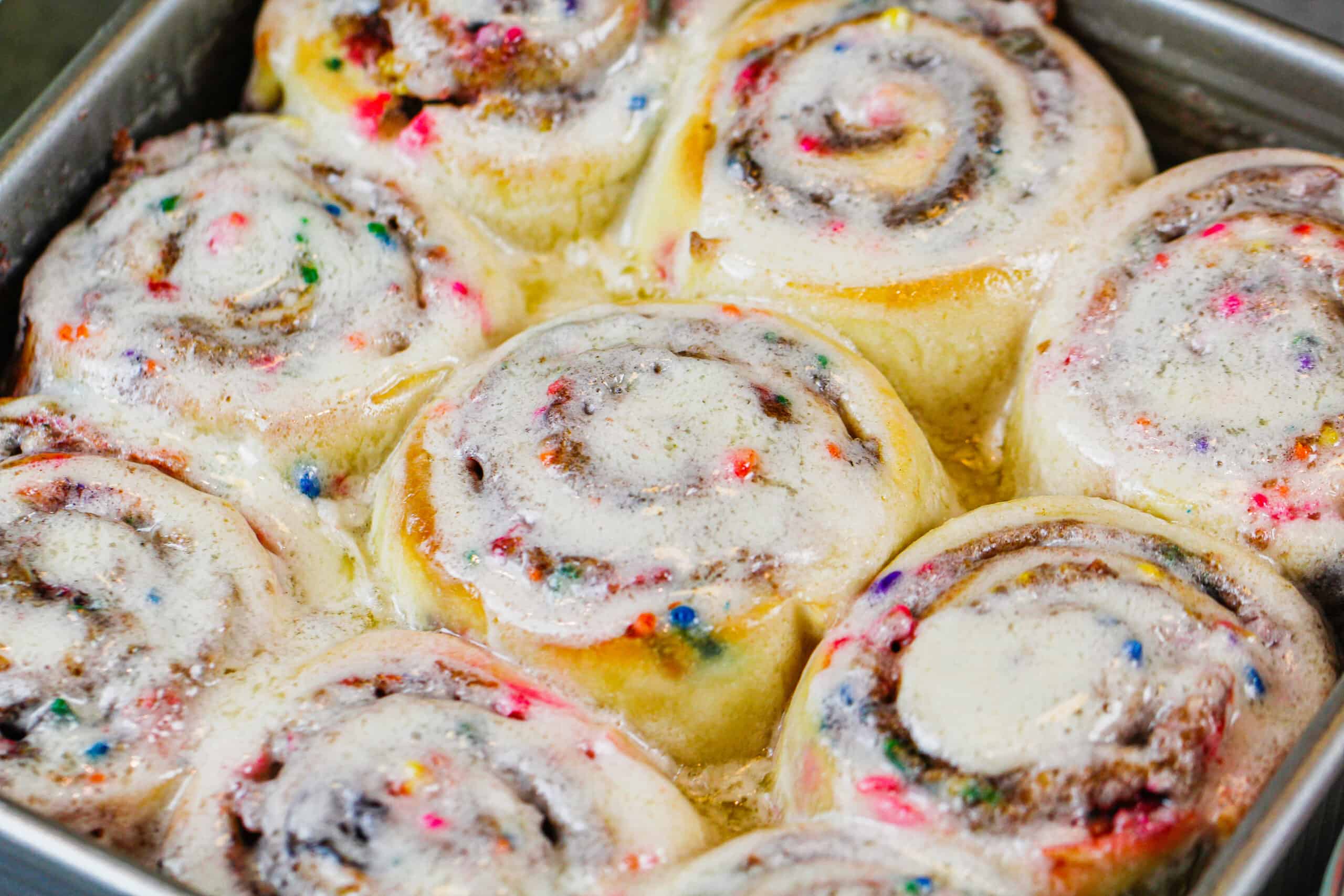 image of warm funfetti sprinkle cinnamon rolls fresh out of the oven with melting frosting