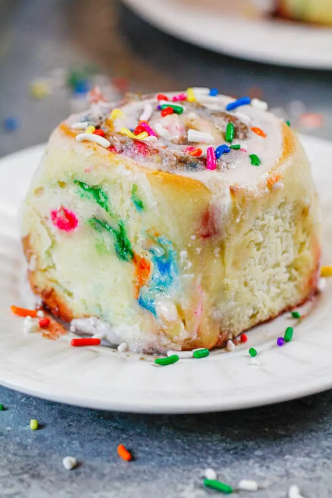 image of a funfetti cinnamon roll made with sprinkles and topped with vanilla icing