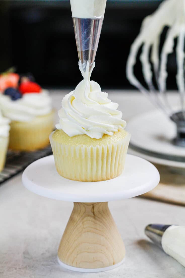 image of stabilized whipped cream frosting made with cream cheese being piped onto a cupcake