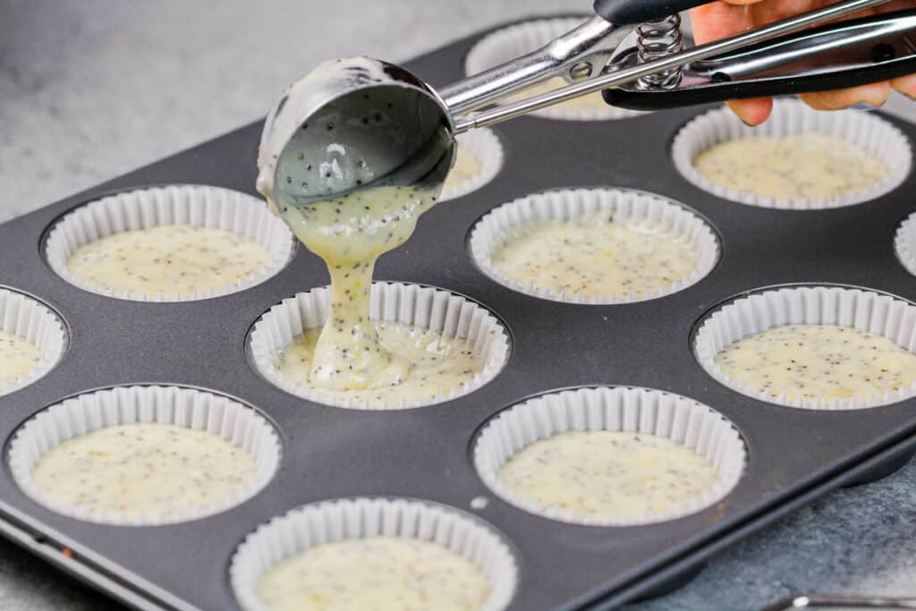 image of lemon poppyseed cupcake batter being added into cupcake liners
