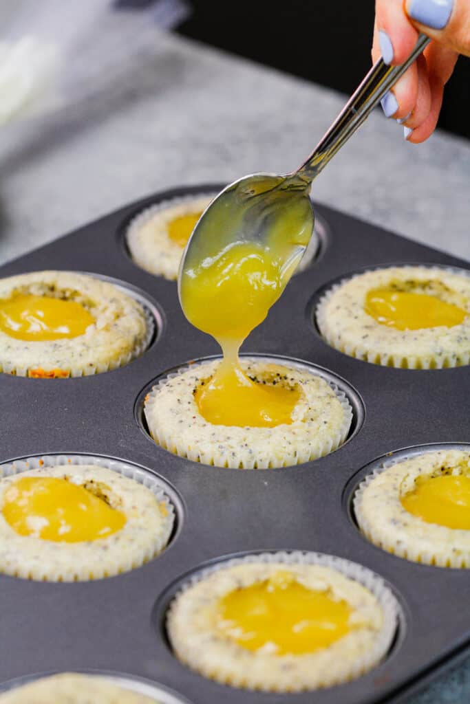 image of lemon curd being added as a filling to lemon poppy seed cupcakes