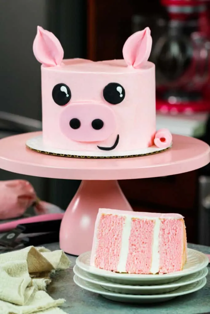 image of pig birthday cake with slice cut out to show pretty pink cake layers