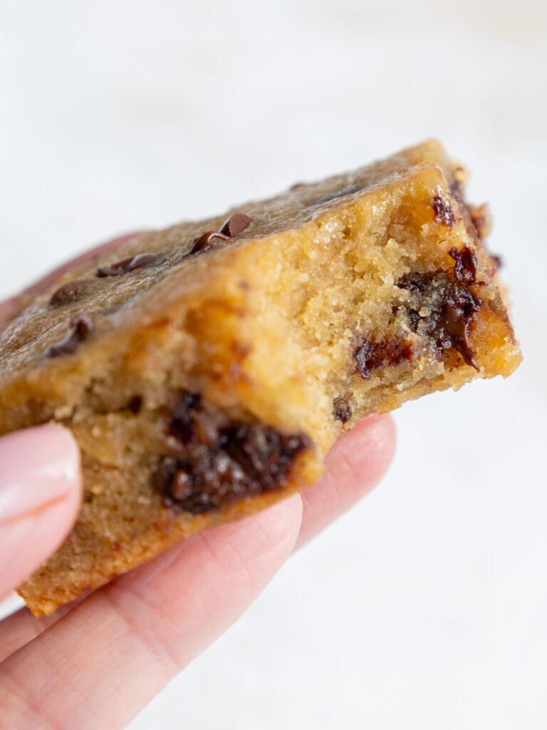 image of a banana chocolate chip bar that's been bitten into to show its tender and moist texture