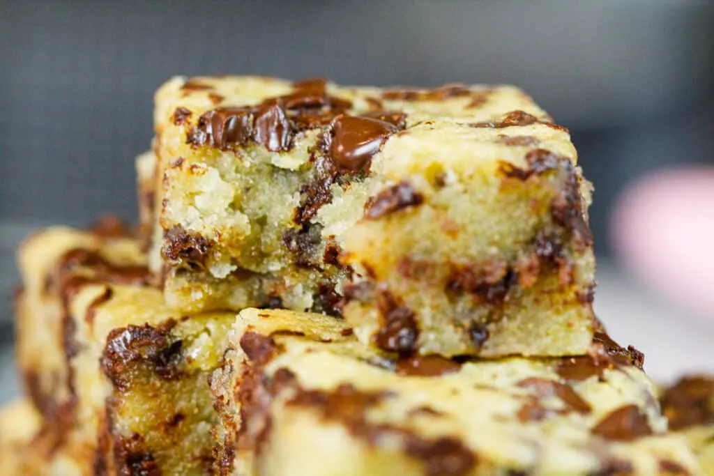 image of chocolate chip banana bars piled together, with a bite taken out of the top bar to show how moist and fudgey it is