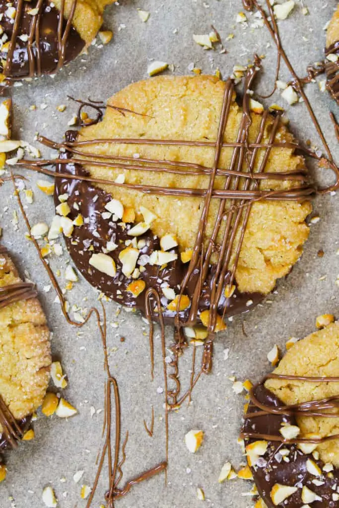 image of chocolate dipped peanut butter cookies decorated with chopped peanuts and flaky sea salt