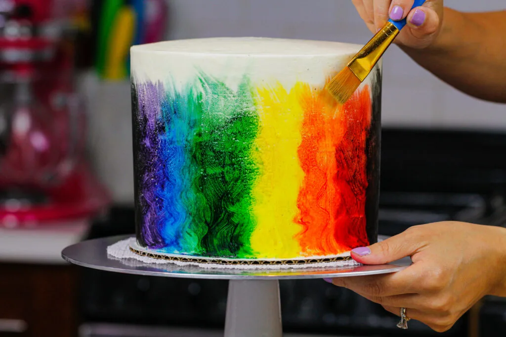 image of pride cake being painted rainbow colors with edible paint made from vodka and gel food coloring.