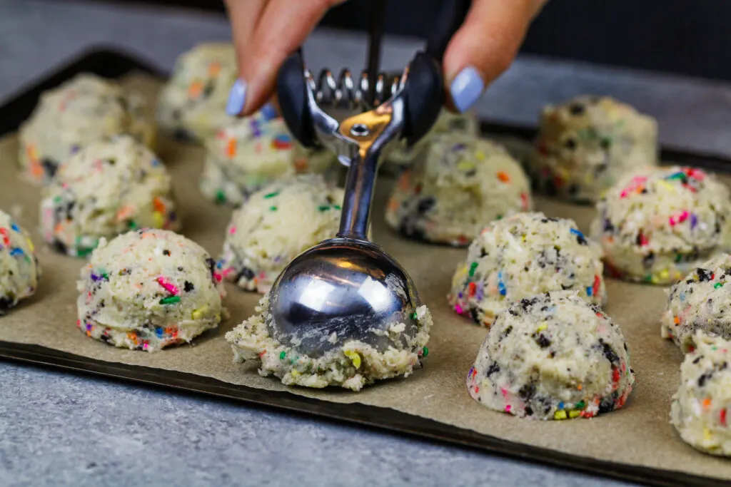 image of funfetti cookie dough that is being scooped before being chilled in the fridge.
