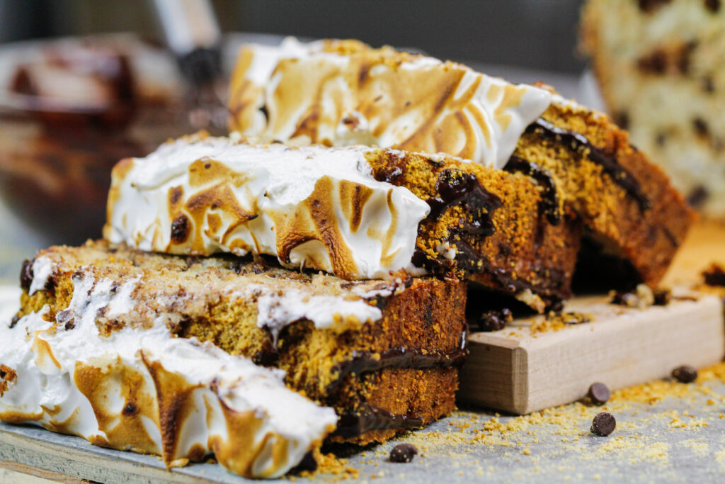 image of smores banana bread loaf cut open to show chocolate chips and toasted marshmallow topping