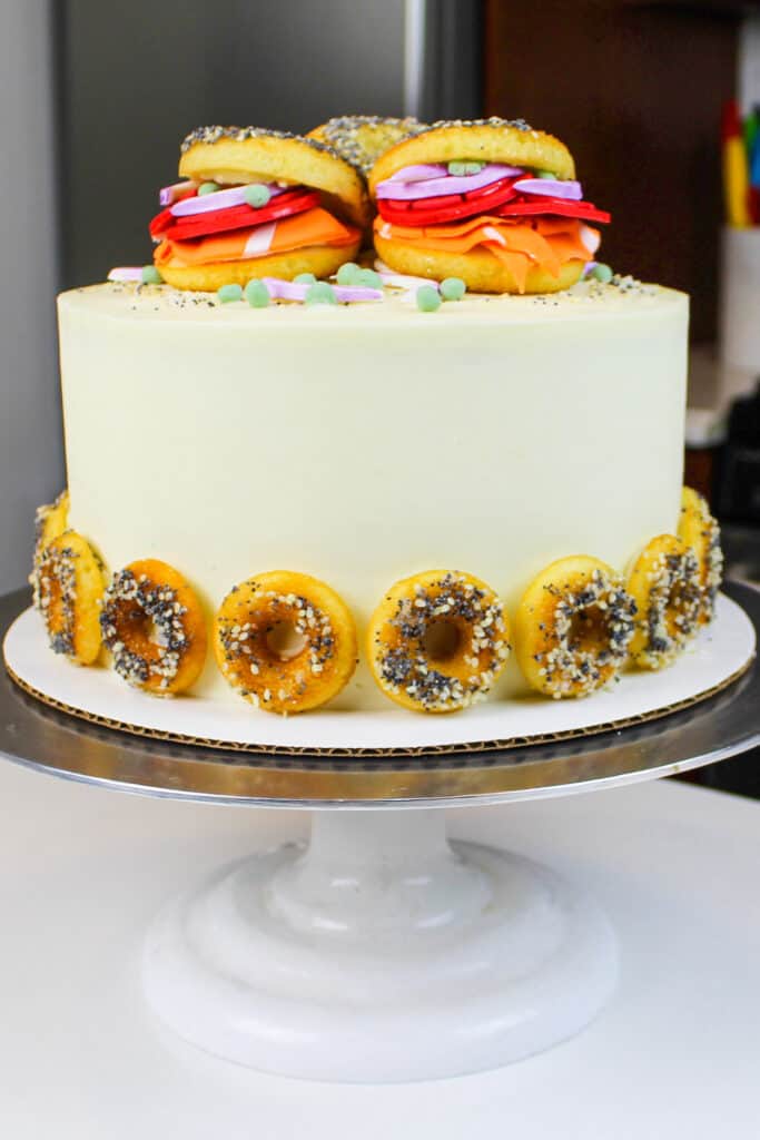 image of bagel cake made with cream cheese frosting and decorated with mini bagel donuts