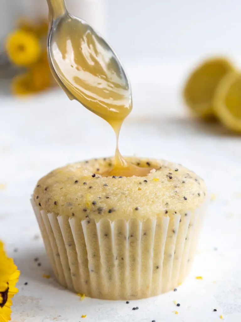 image of a lemon poppy seed cupcake being filled with lemon curd