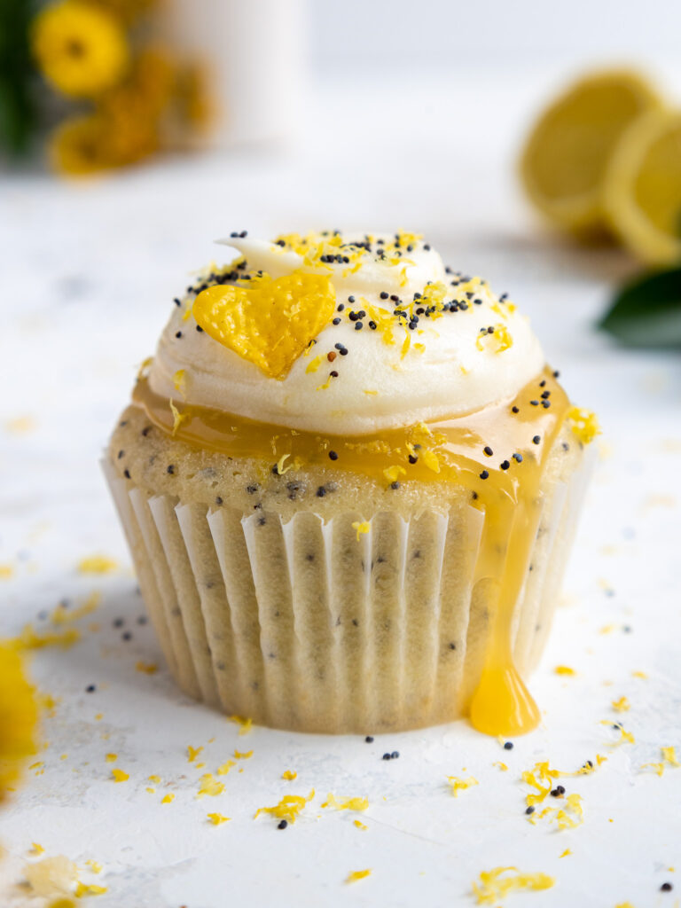 image of a cute lemon poppy seed cupcake that's been frosted with lemon cream cheese frosting and filled with lemon curd