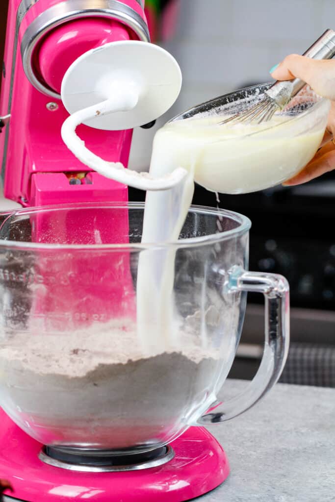 image of milk being poured into dry ingredients to make a chocolate enriched dough