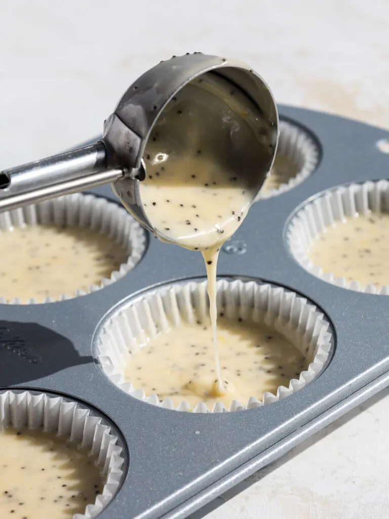 image of lemon poppy seed cupcake batter being scooped into cupcake liners with a cookie scoop