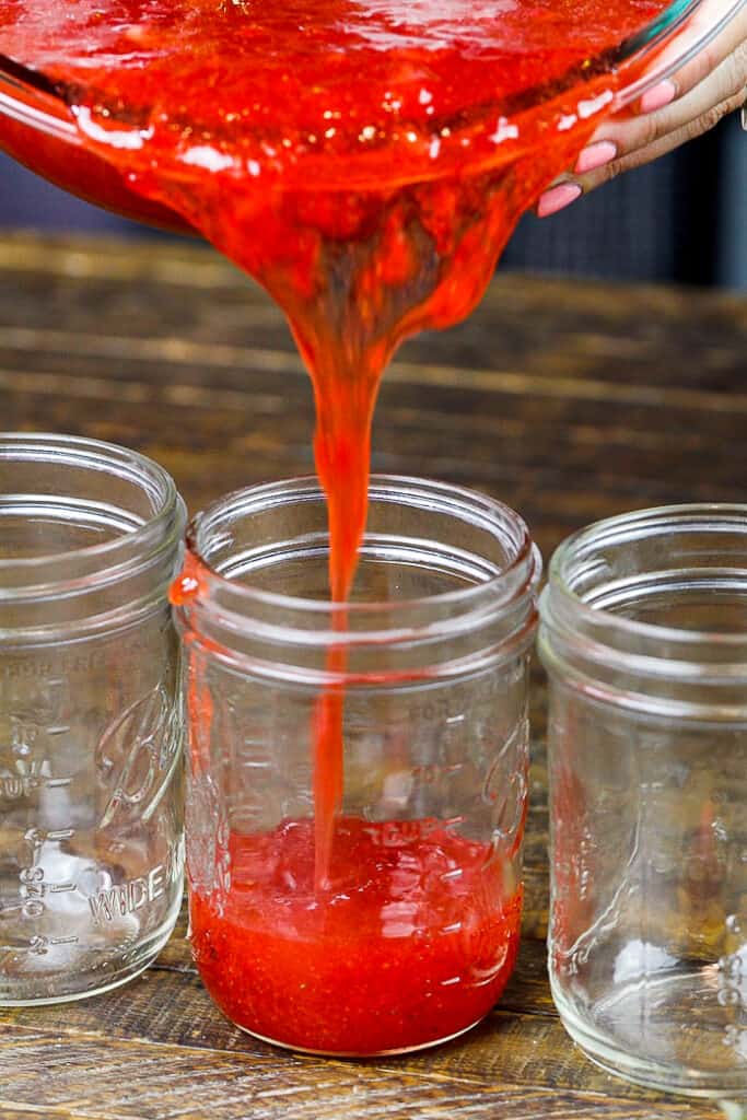 image of certo strawberry freezer jam being poured into a wide mouthed mason jar
