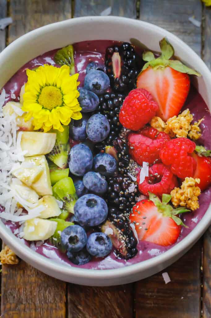 image of a pretty acai bowl topped with coconut, chia seeds, bananas, strawberries, kiwi, blueberries, strawberries and blackberries
