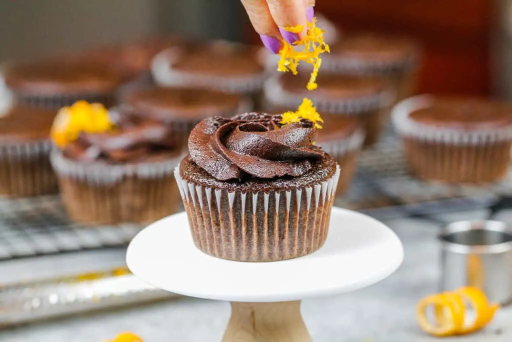 image of orange zest being added to an orange chocolate cupcake