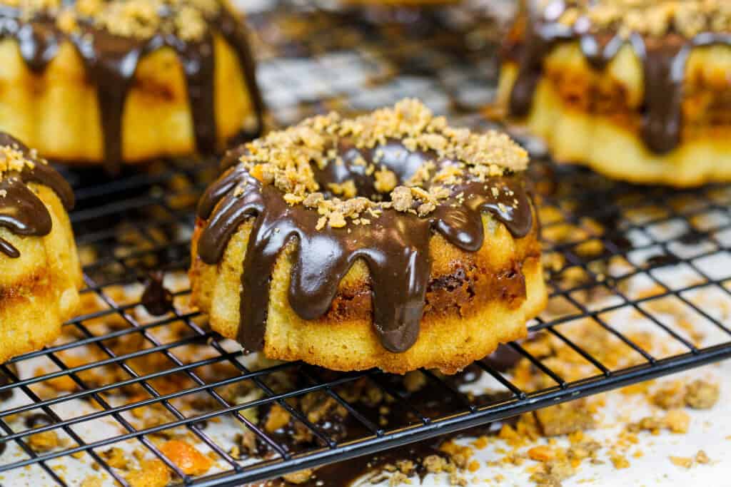 image of mini butterfinger bundt cakes topped with a chocolate peanut butter glaze