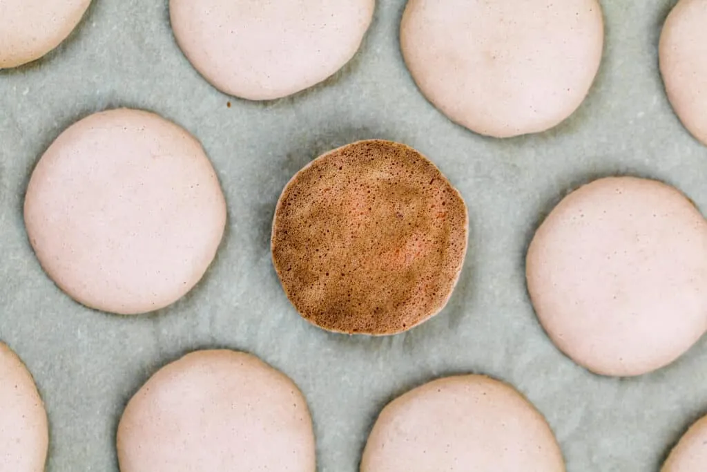 image of an overcooked macaron shell that has a brown bottom
