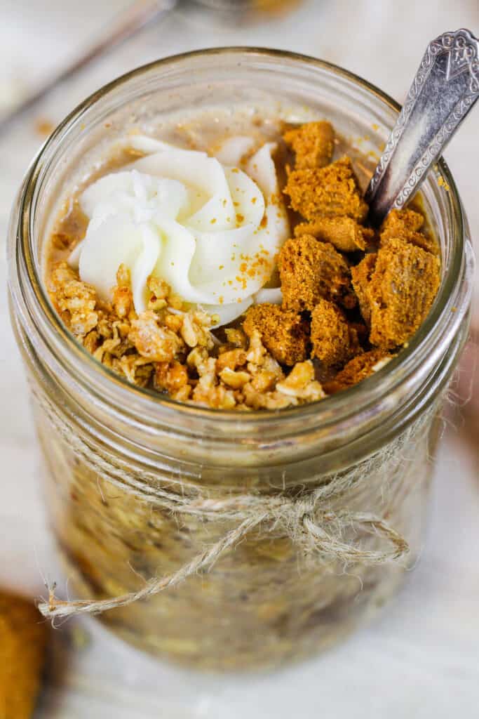 image of a jar of biscoff overnight oats topped with whipped cream and biscoff cookies
