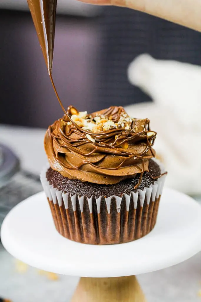 image of a Nutella cupcake being drizzled with additional Nutella to decorate it