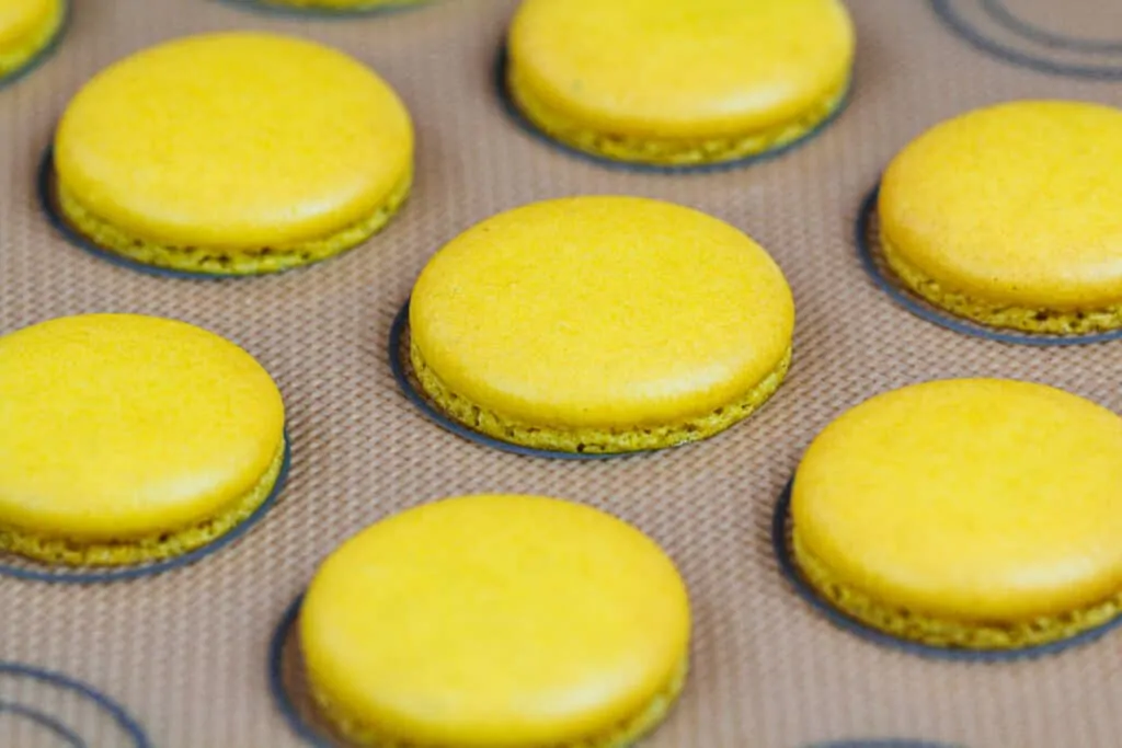 image of yellow macaron shells that have been baked and are cooling before being filled