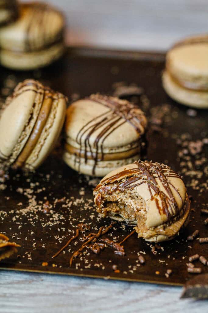 image of french chocolate macarons that have been bitten into to show their perfect chewy texture and delicious chocolate filling