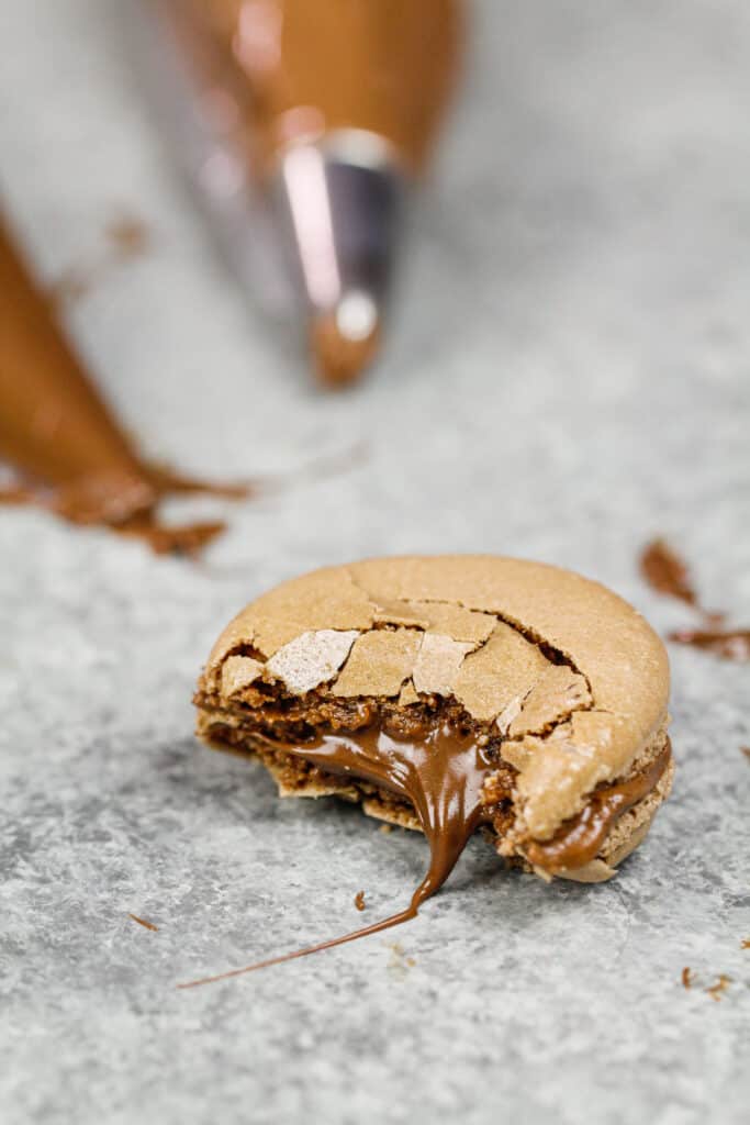image of a Nutella macaron that's been bitten into to show it's Nutella filling