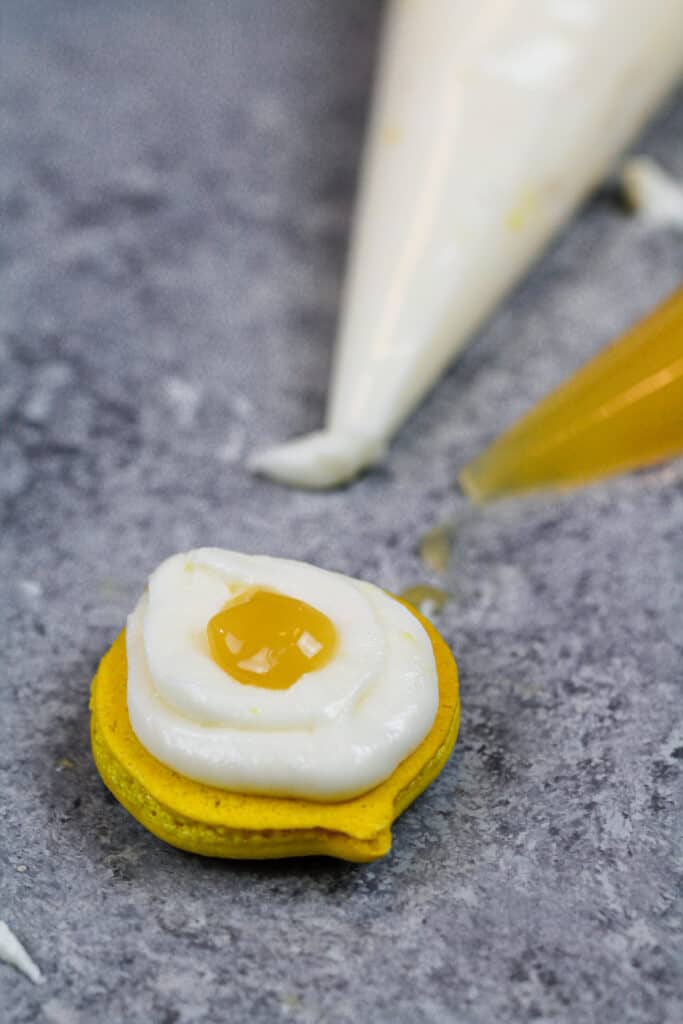 image of a lemon macaron that's filled with lemon curd and a fresh lemon buttercream