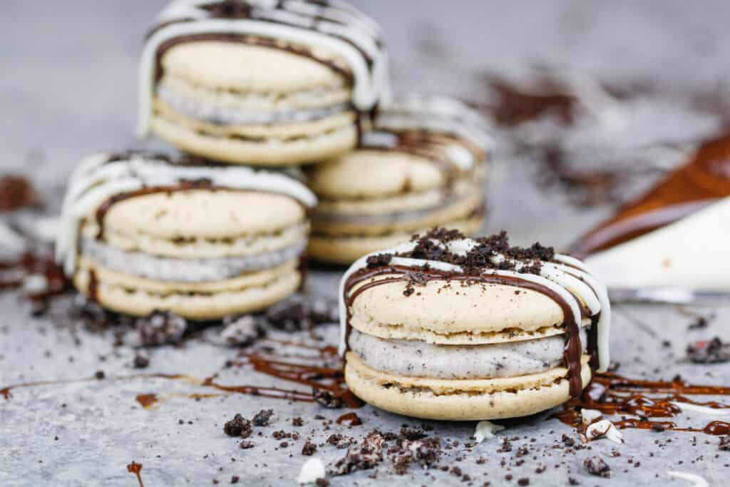 image of oreo macarons decorated with a chocolate drizzle and oreo crumble