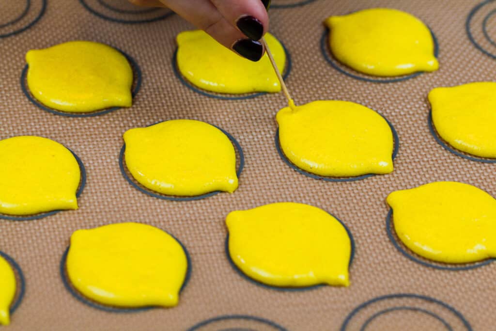 image of lemon shaped macaron shells that have been piped and are ready to be baked