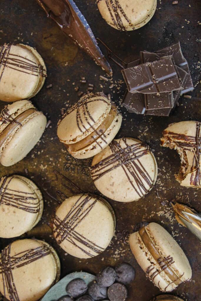 image of chocolate macarons shot overhead to show how they're decorated with a chocolate drizzle and some chocolate shavings