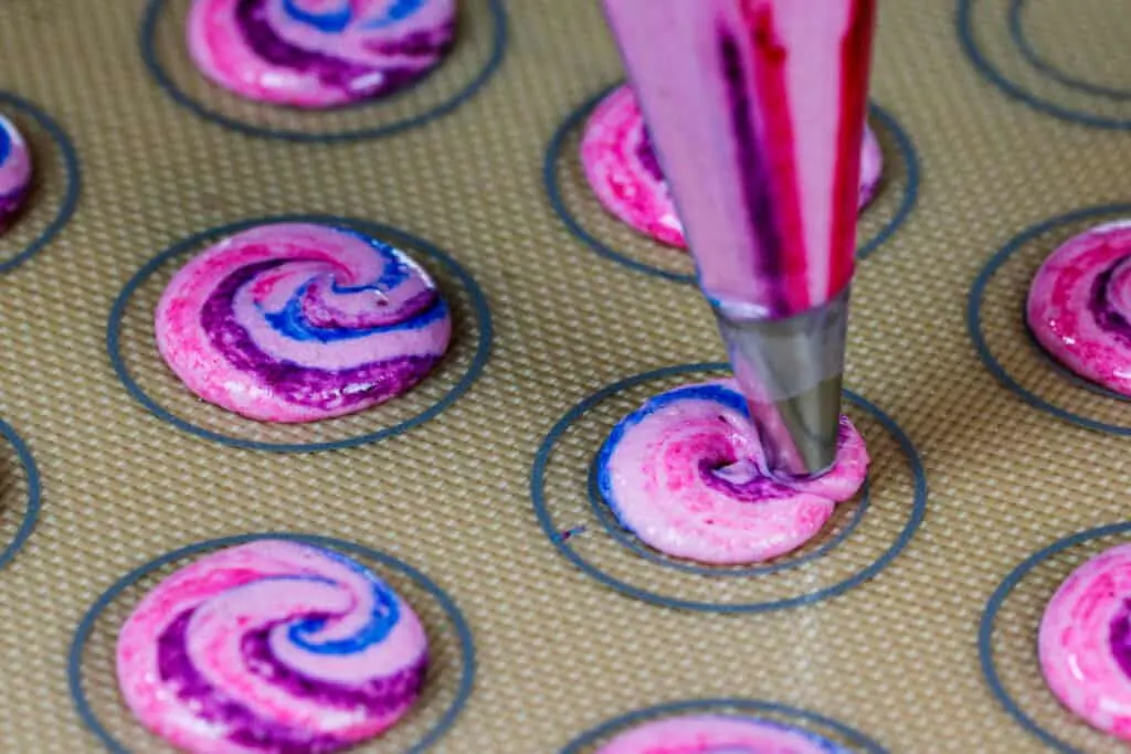 image of colorful cotton candy macarons being piped onto a silpat mat