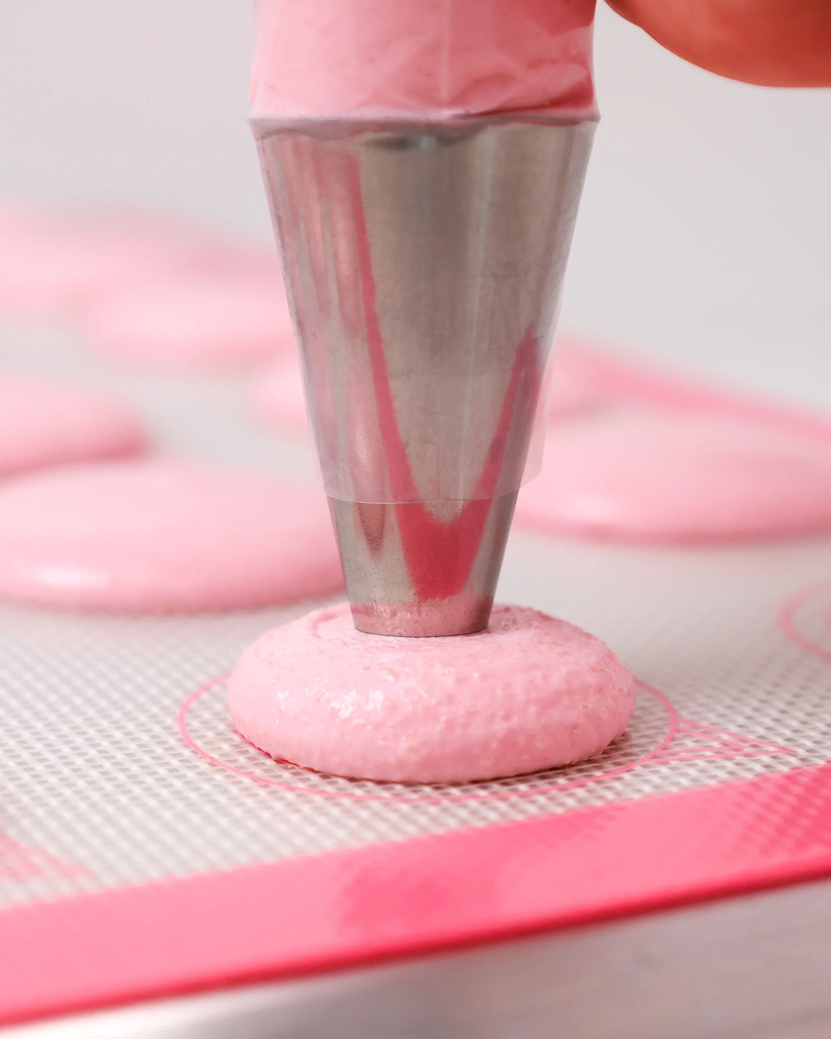 image of pink Italian macarons being piped onto a silpat mat
