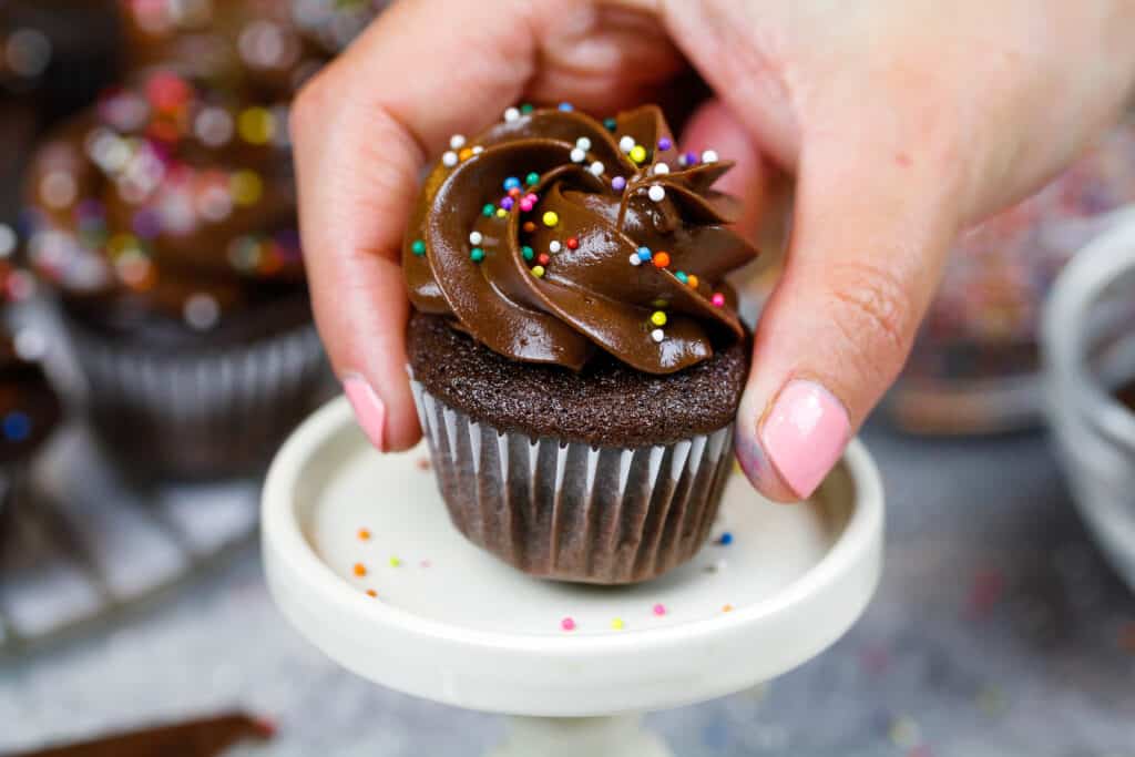 image of a mini chocolate cupcake being placed on a mini cake stand