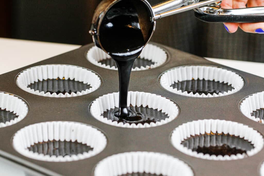 image of black cupcake batter being poured into cupcake liners to make soot sprite cupcakes