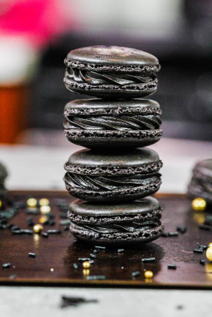 bilde av svarte makroner laget med fransk teknikk og fylt med svart kakaosmørkrem