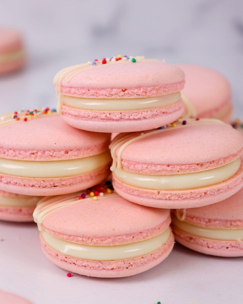 image of Italian macarons filled with white chocolate ganache topped with white chocolate and sprinkles