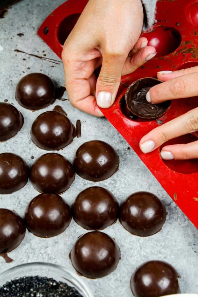 image of chocolate shells being removed from a silicone mold to make a hot chocolate bombs recipe