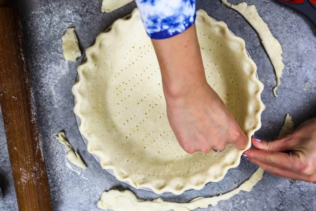 image of an all butter pie crust being crimped using my knuckle and fingers