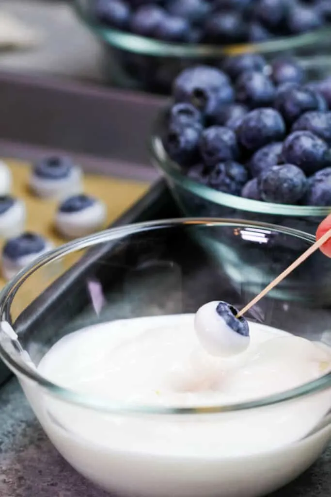 image of a blueberry being dipped in greek yogurt to make a healthy snack