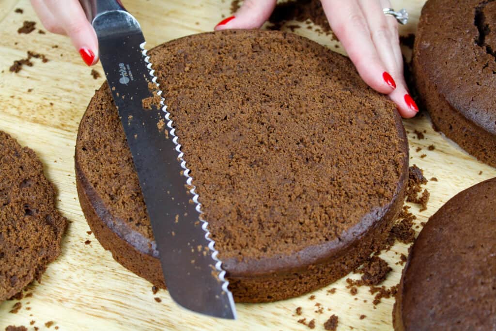 image of chocolate cake layers being leveled with a serrated knife