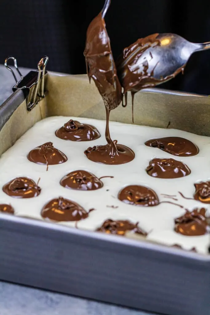 image of nutella being dropped and swirled into cheesecake bars
