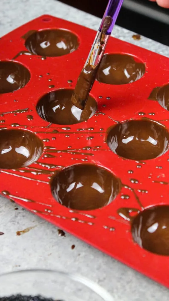 image of a silicone mold being filled with chocolate to make homemade DIY hot chocolate bombs