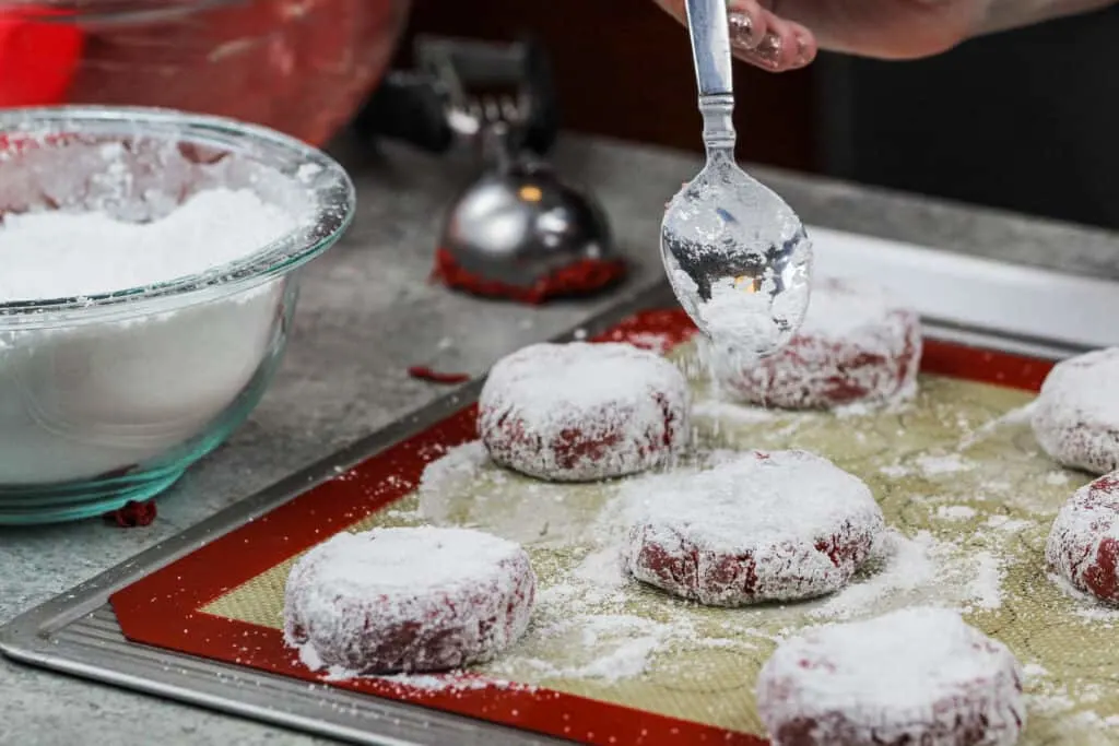 image of red velvet crinkle cookies that have been dunked in powdered sugar and are ready to be baked