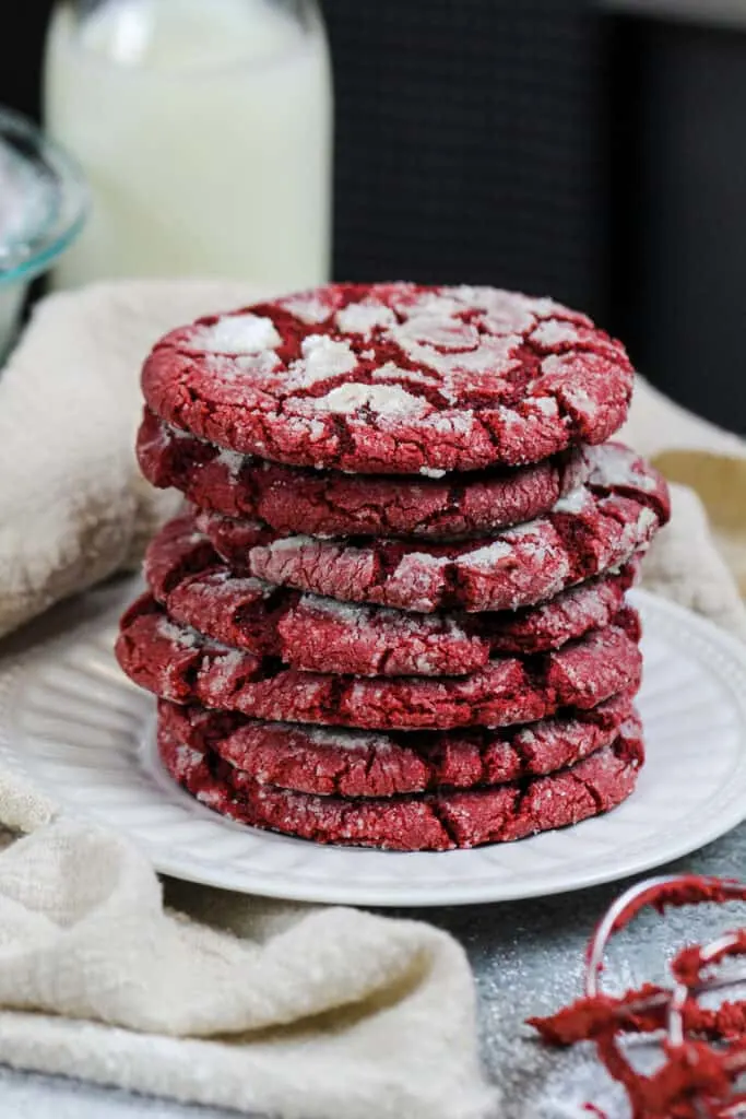 image of red velvet crinkle cookies that have been stacked on a small plate and are ready to be eaten