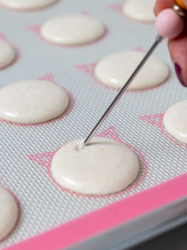 image of air bubbles being popped with a scrap in a macaron shell