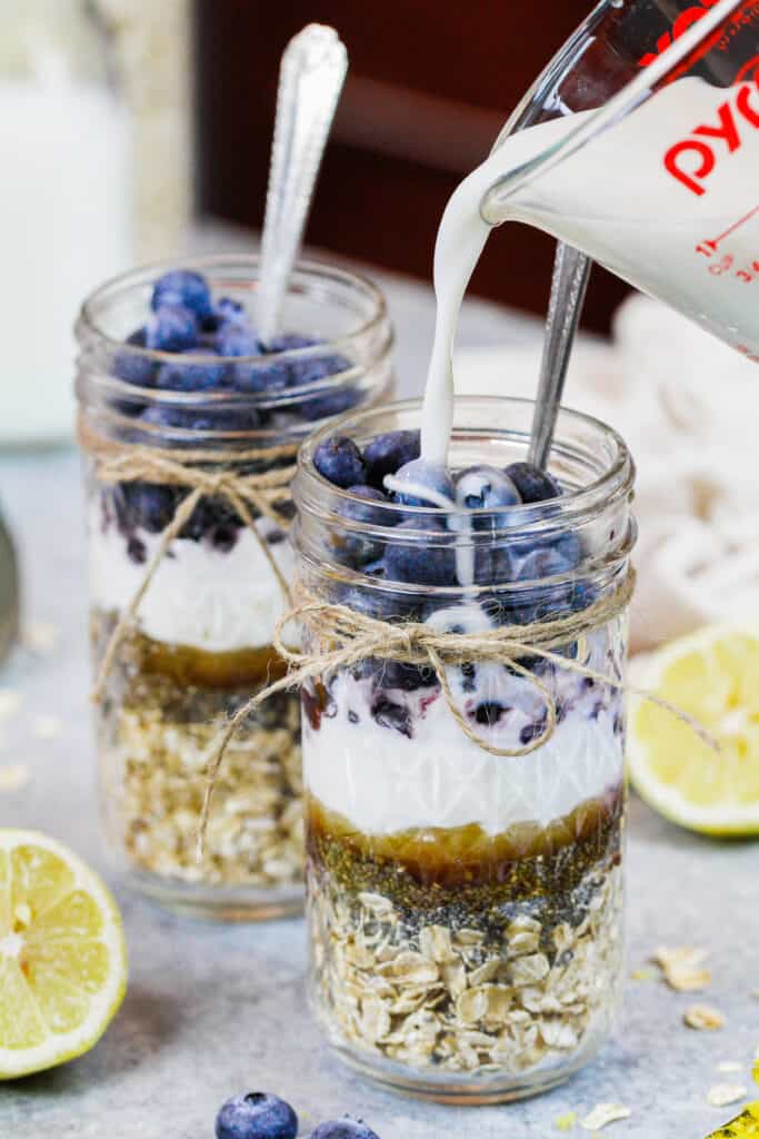 image of almond milk being poured into blueberry overnight oats