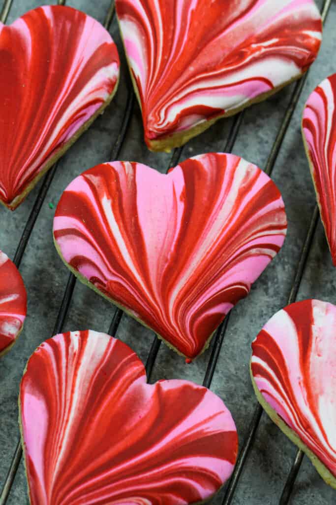 image of heart shaped sugar cookies that are soft and chewy and have been decorated with beautiful marbled red and pink royal icing