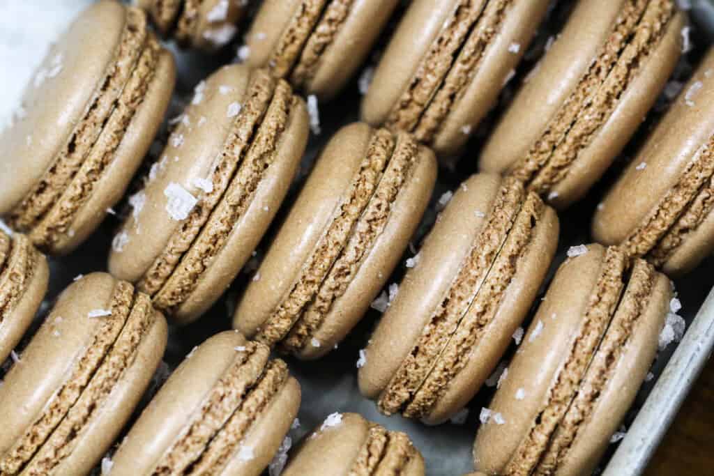 image of chocolate macaron shells that have been sprinkled with sea salt to make salted caramel macarons